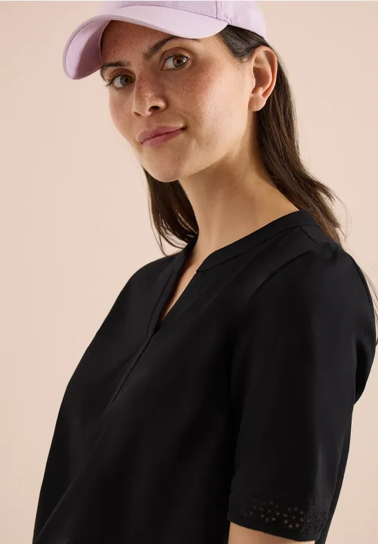 Junge Frau in schwarzem Shirt und hellvioletter Basecap, seitliche Aufnahme