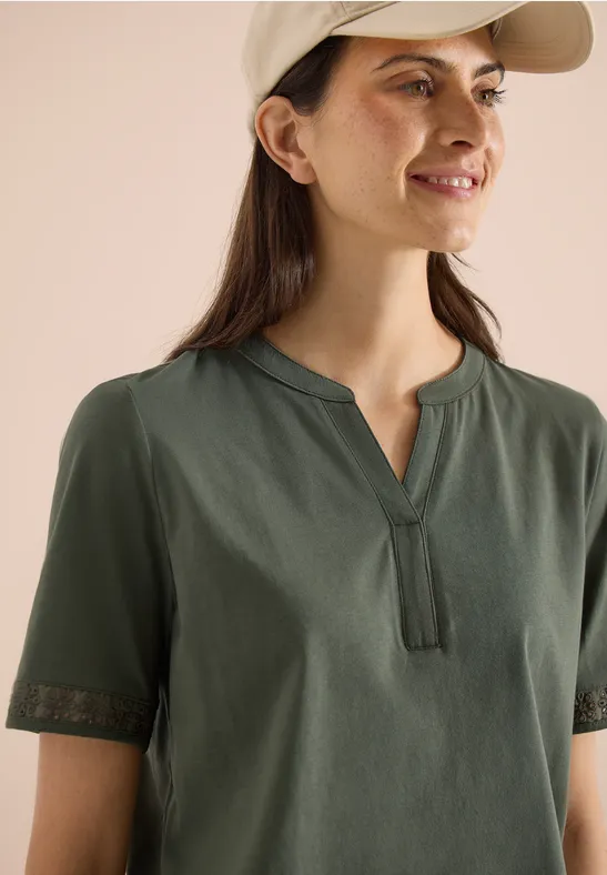 Dunkelgrünes Damen-Shirt mit kurzen Spitzenärmeln und V-Ausschnitt.