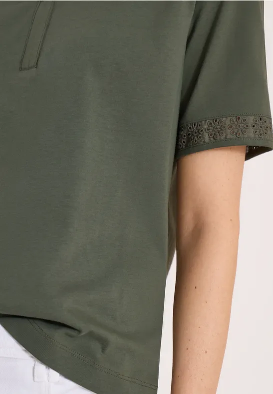 Detail eines olivgrünen Kurzarmshirts mit feiner Häkelspitze am Ärmel.