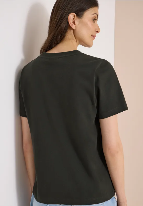 Rückansicht einer Frau mit dunklem, kurzärmligem Shirt vor hellem Hintergrund.