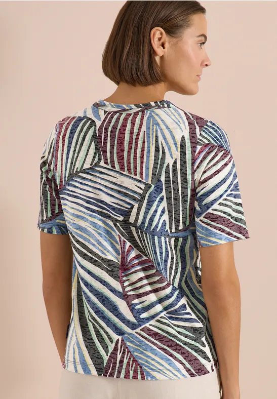 Rückenansicht einer Frau in einem kurzärmeligen, abstrakt gestreiften, bunt gemusterten Shirt.