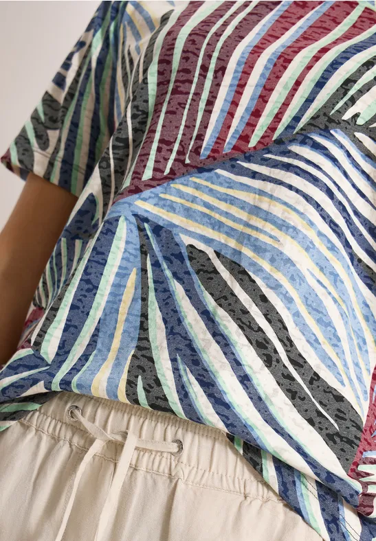 Nahaufnahme eines Oberkörpers in buntem, gestreiftem T-Shirt und beigen Hosen mit Gummibund.