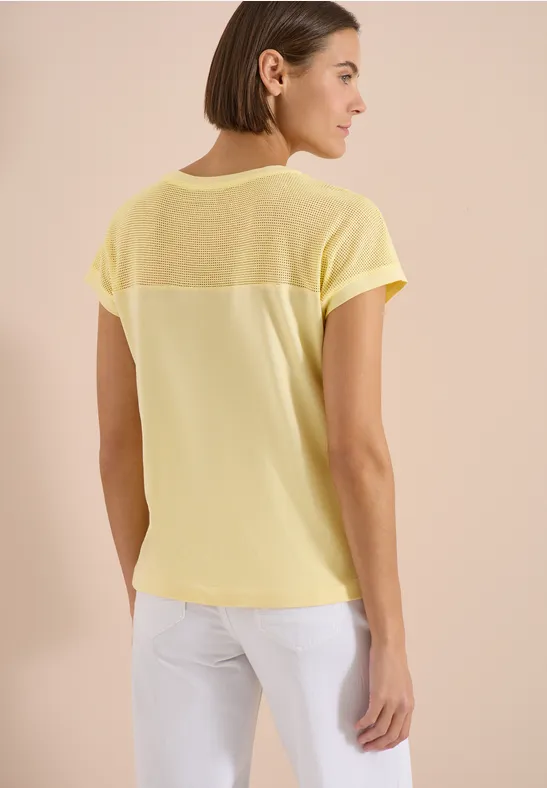 Frau von hinten in lockerem gelbem T-Shirt mit transparentem Rückenbereich.