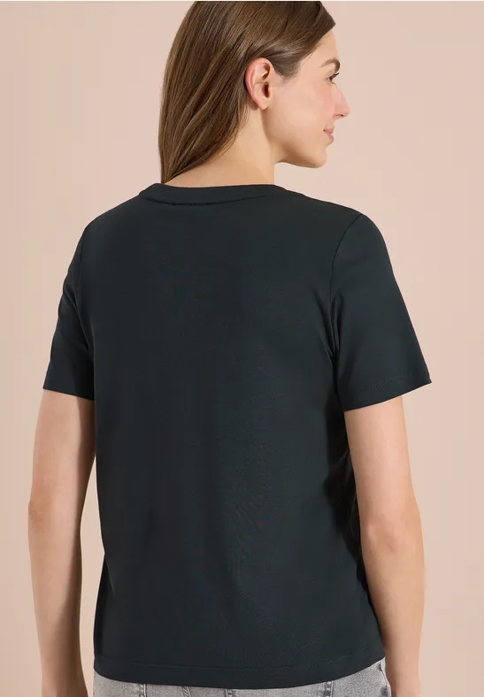 Rückenansicht einer Frau in einem schwarzen, kurzärmeligen T-Shirt vor beigem Hintergrund.