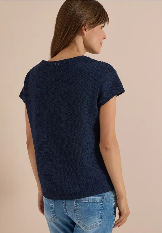 Frau von hinten in navyblauem Strickshirt und Jeans