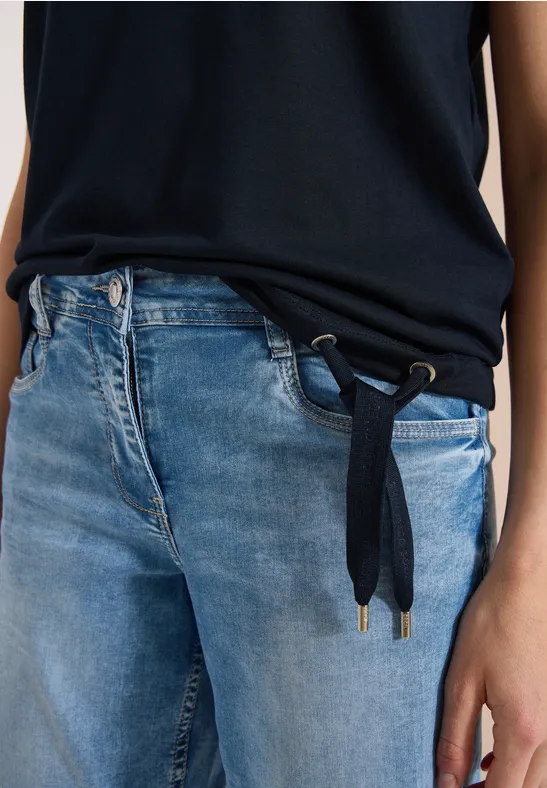 Nahaufnahme eines Oberkörpers in blauer Jeans mit dunkelblauem Kordelgürtel und schwarzem Oberteil.