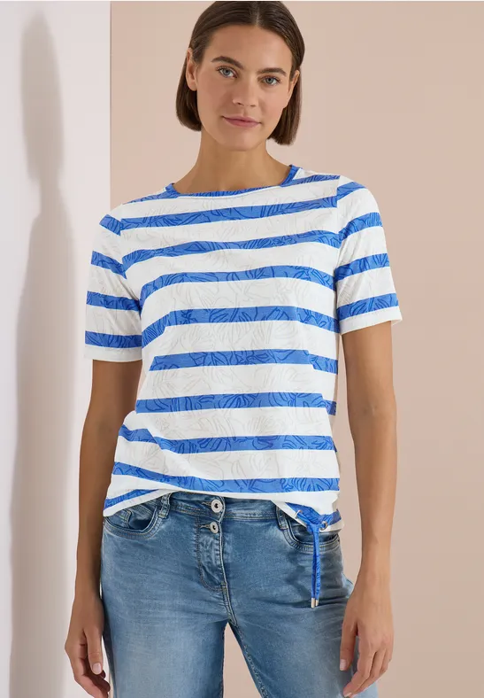 Persoon voor neutrale achtergrond met blauw-wit gestreept T-shirt en blauwe spijkerbroek.