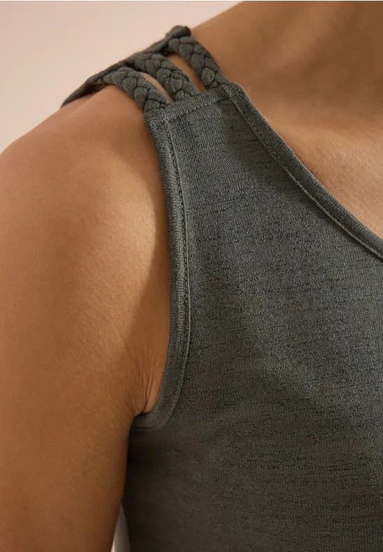 Gros plan sur une personne portant un débardeur gris à bretelles tressées