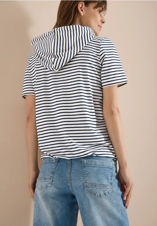 Frau von hinten in gestreiftem T-Shirt mit Kapuze und blauen Jeans.