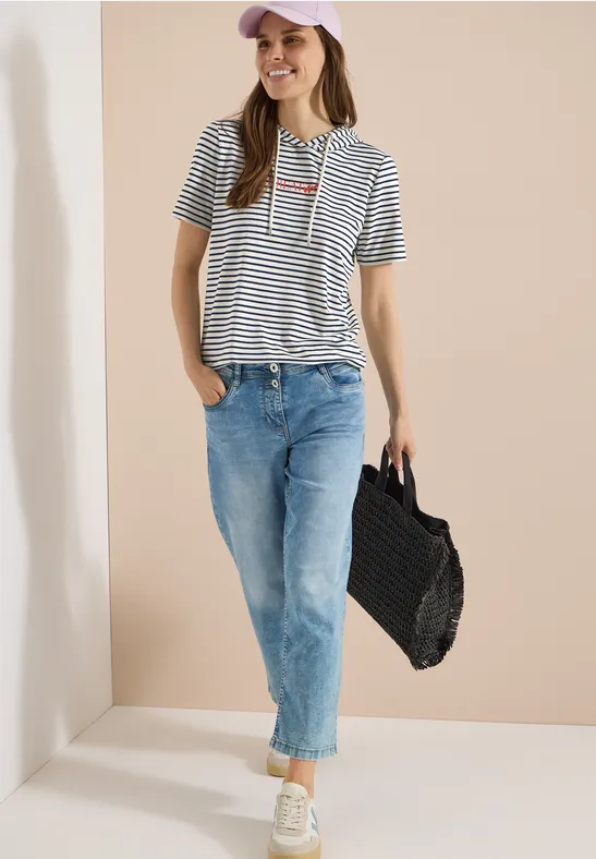 Frau mit Streifenshirt, blauen Jeans und einer geflochtenen Tasche.