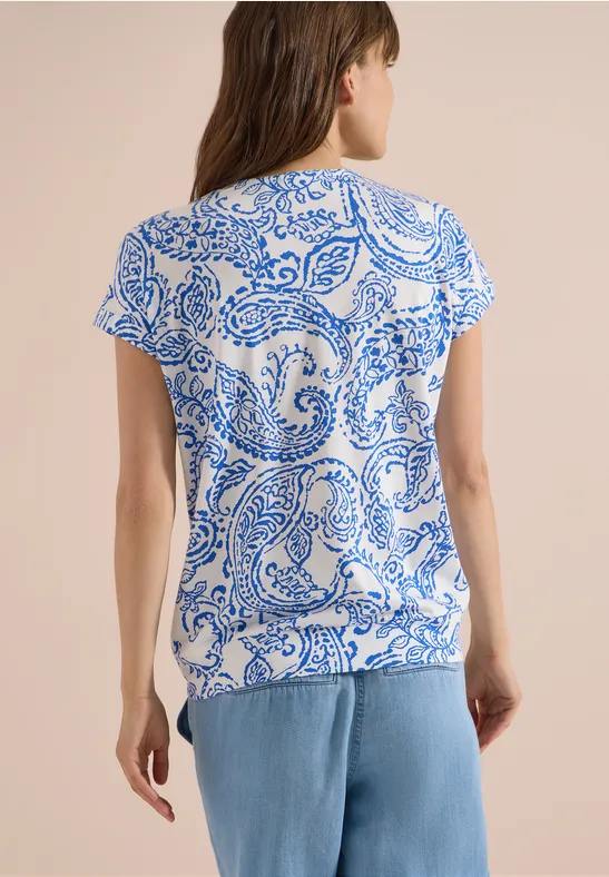Rückansicht einer Frau mit weiß-blau gemustertem T-Shirt und hellblauen Jeans.