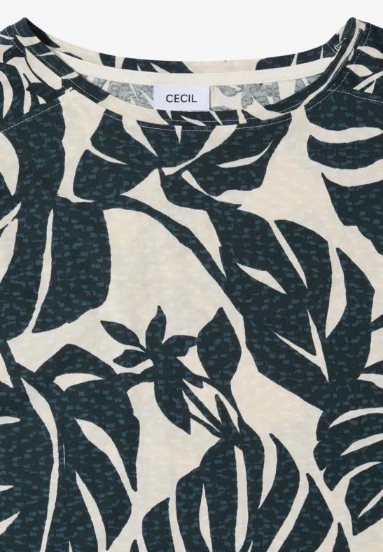 Helle Bluse mit dunkelblauem Tropenblatt-Print auf cremefarbenem Hintergrund.