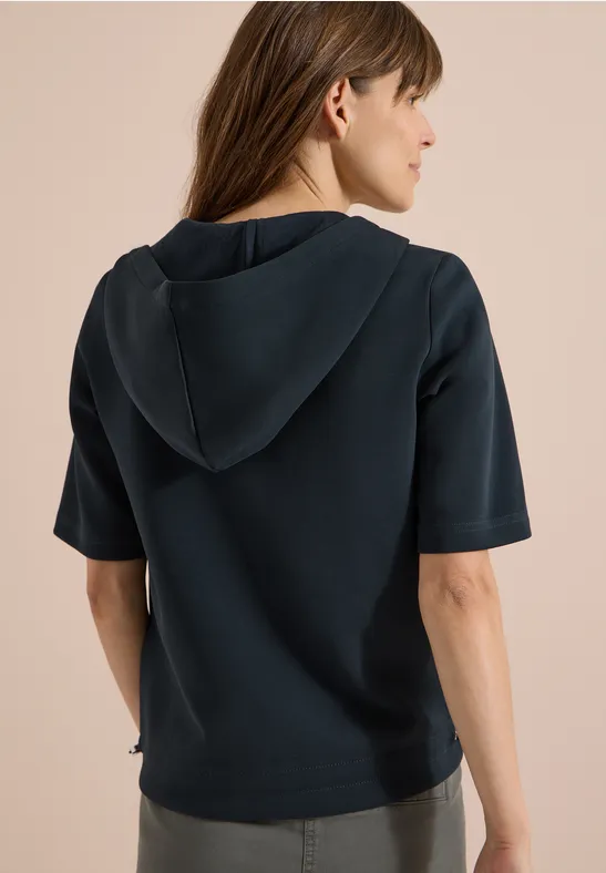 Femme vue de dos portant un t-shirt à capuche bleu foncé à manches courtes.
