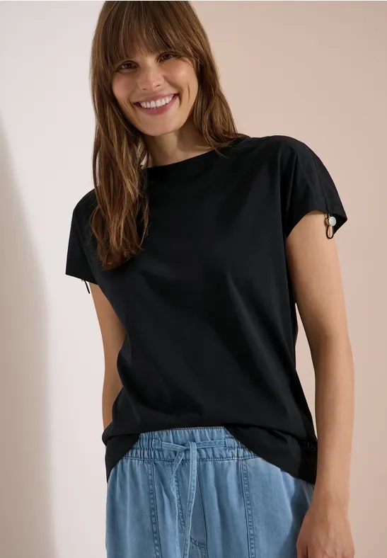 Personne au visage flou porte un t-shirt noir et un jean bleu.