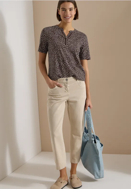 Tenue élégante : top manches courtes à motifs, pantalon droit clair et sac bleu clair.