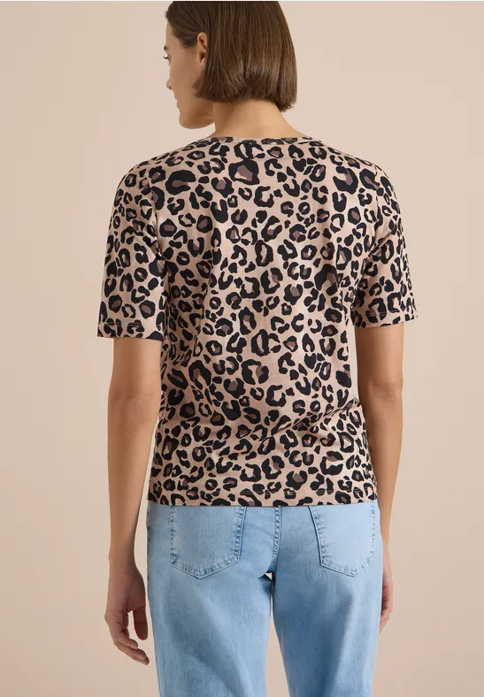 Femme de dos en jean et t-shirt beige à manches courtes, imprimé léopard noir.