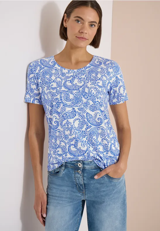 Femme en t-shirt bleu à motif paisley et jean bleu.