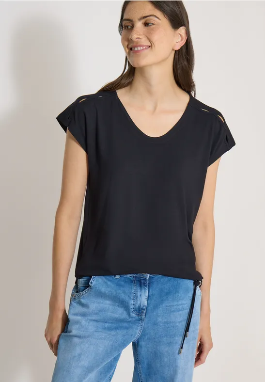 Femme portant un t-shirt noir à col en V et manches courtes avec jeans bleus.