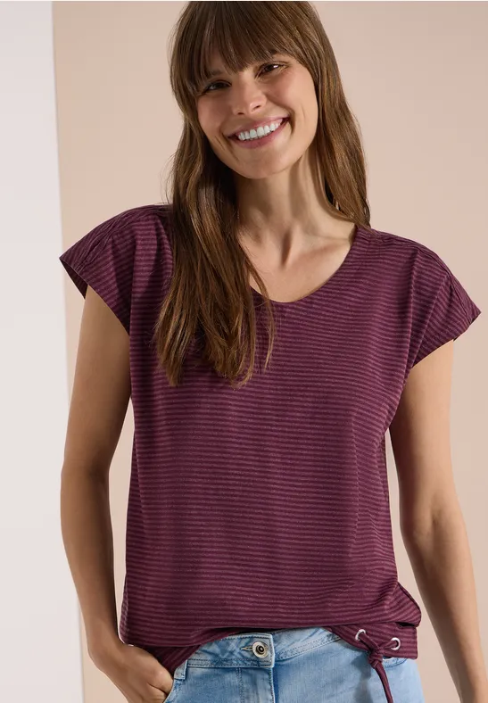 Femme en t-shirt violet à fines rayures sur fond neutre.