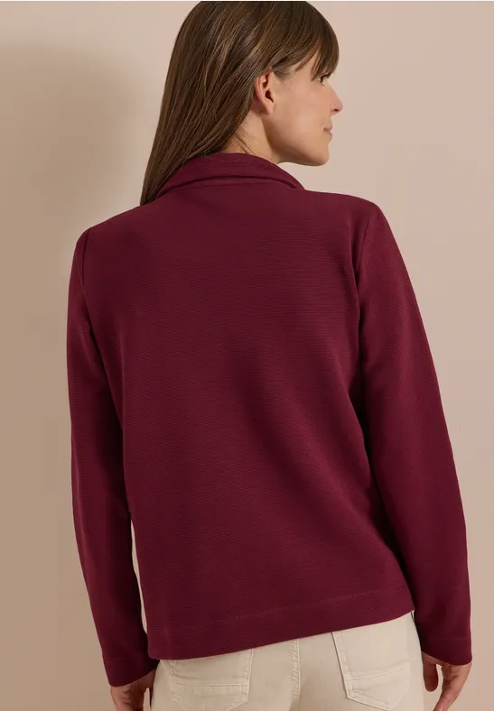 Eine Frau von hinten trägt eine weinrote Fleecejacke.