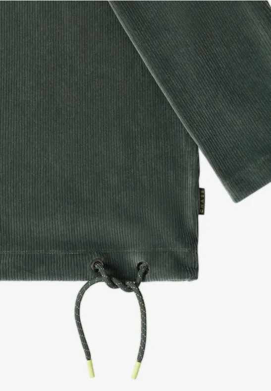 Détail d’un tee-shirt en velours côtelé vert foncé, cordon de serrage à la base et petit label sur la couture.