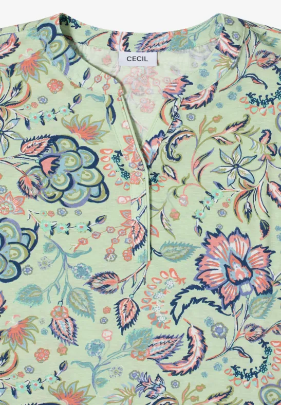 Blouse vert clair à motif floral coloré, encolure en V et coupe ample.