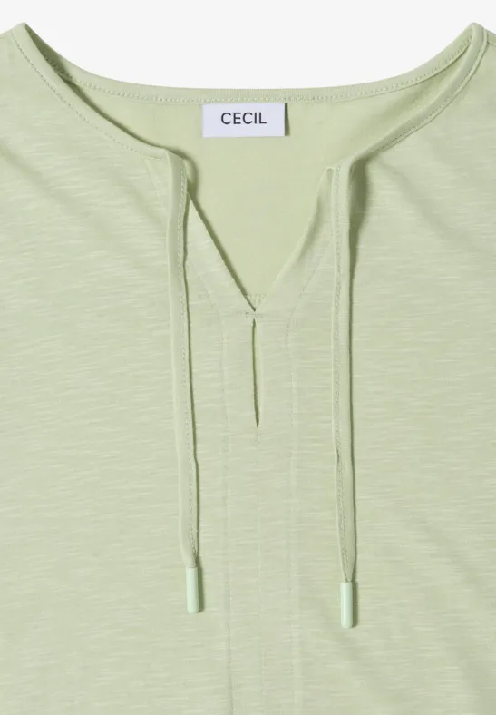 T-shirt à manches longues vert pâle, col V à cordons, étiquette 'CECIL'.