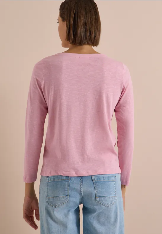 Personne de dos portant un tee-shirt rose à manches longues et un jean bleu.