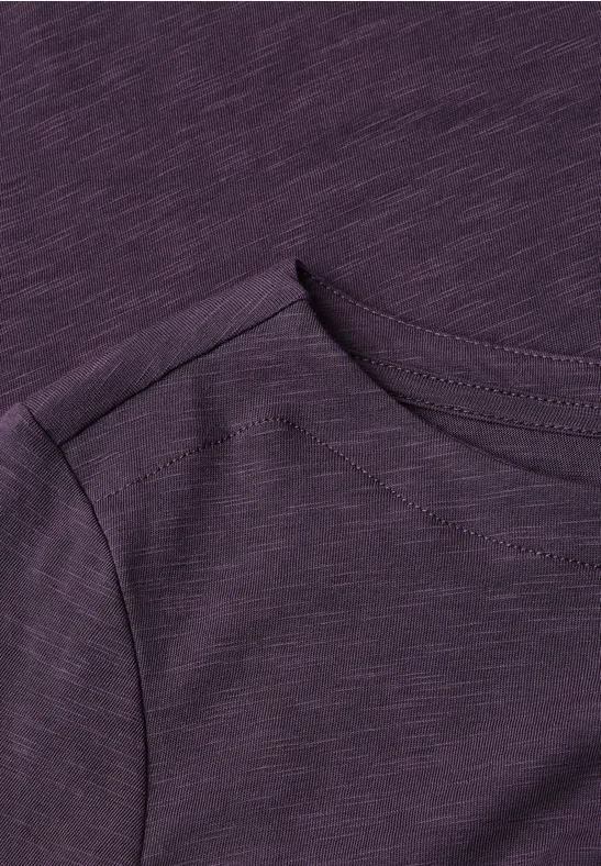 Gros plan d'un t-shirt violet à col rond et épaule visible.