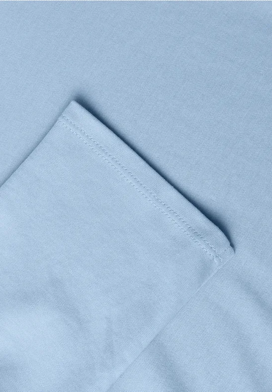 Helles blaues Stoffstück mit Naht und umgeschlagener Ecke.