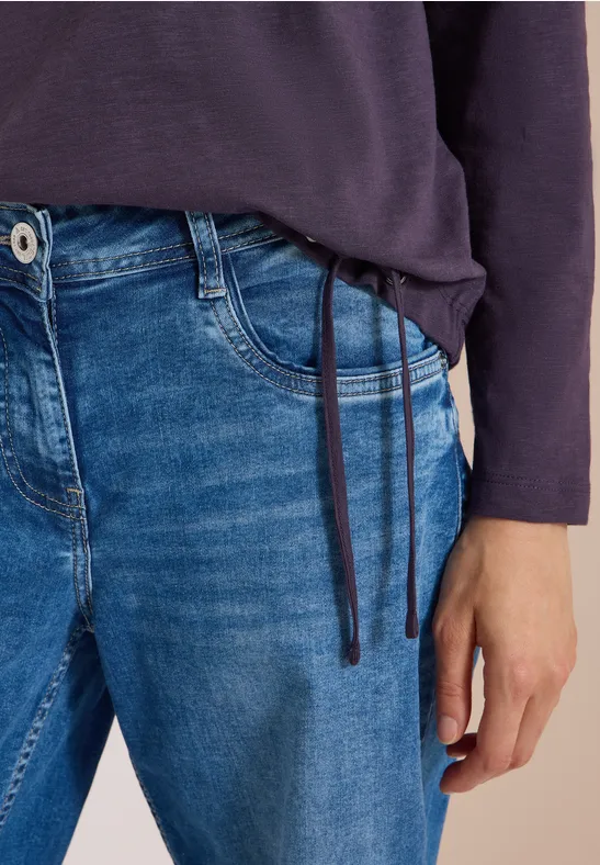 Une personne porte un jean bleu et un pull à manches longues bleu foncé avec cordons.