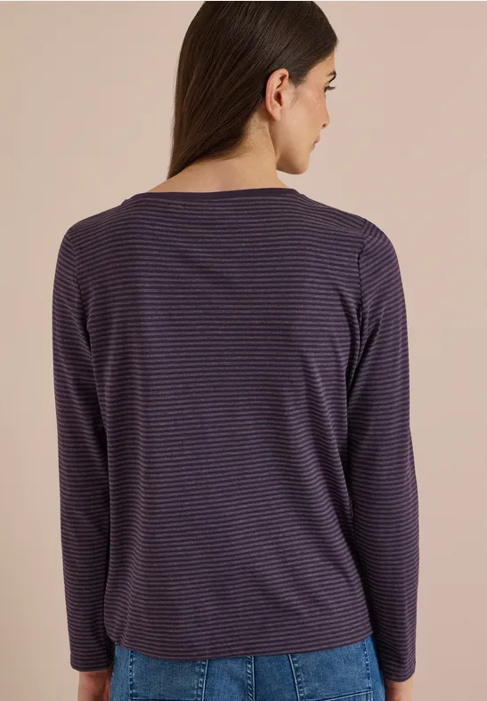 Femme vue de dos, portant un haut à manches longues violet à fines rayures.