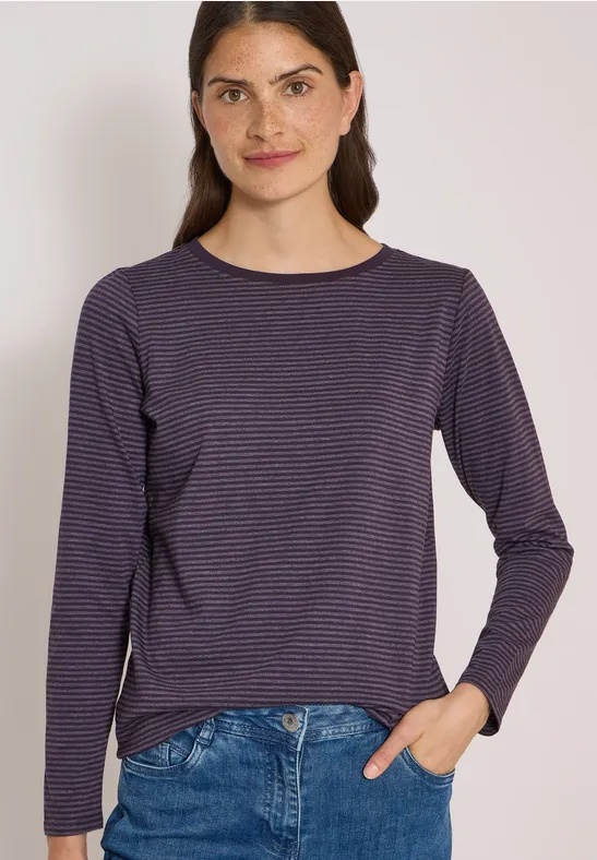 Femme en pull à rayures bleu marine et blanc et jean sur fond clair.