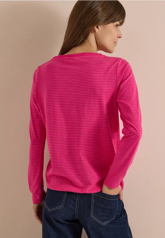 Eine Frau trägt von hinten gesehen ein pinkes, gestreiftes Langarmshirt und Jeans.