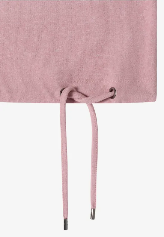 Gros plan sur le bas d’un vêtement rose avec cordon de serrage et lien décoratif.