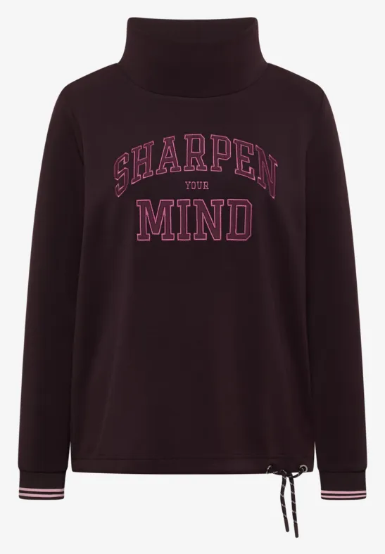 Dunkelvioletter Rollkragenpullover mit pinkem 'SHARPEN THE MIND'-Schriftzug, Saumkordel und gestreiften Bündchen.