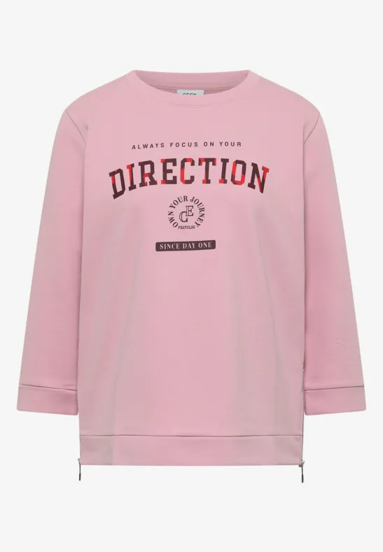 Sweatshirt rose à manches longues, cordon de serrage à l’ourlet et inscription 'DIRECTION' en bordeaux.