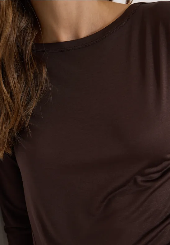 Gros plan sur un torse en t-shirt marron à manches longues et cheveux visibles.