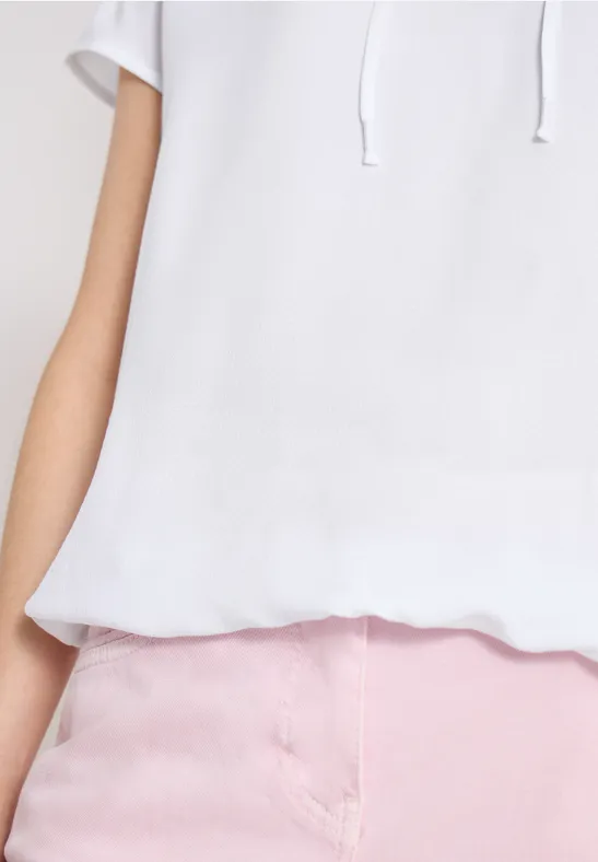Person in weißem Kapuzenpullover und rosa Hose, nur Oberkörper und Taille sichtbar.