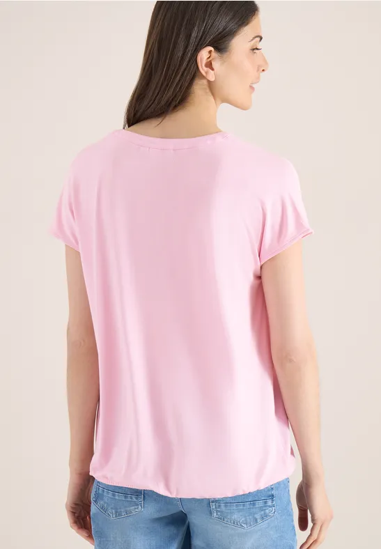 Personne vue de dos porte un t-shirt rose ample, un jean bleu et des cheveux mi-longs lisses.