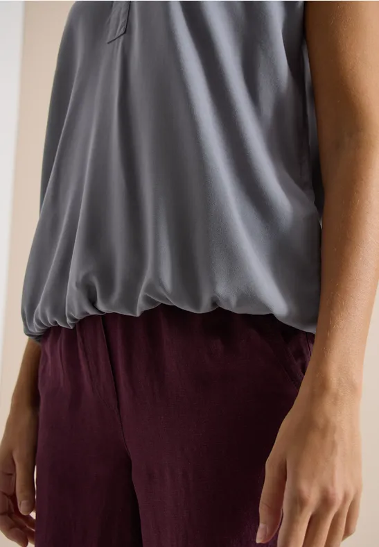 Dunkelgraue fließende Bluse kombiniert mit locker sitzender bordeauxroter Hose, seitliche Armansicht.