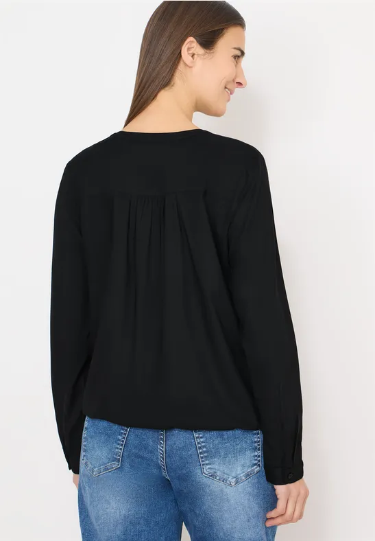 Rückansicht einer Person in schwarzem Langarmshirt und blauen Jeans vor weißem Hintergrund