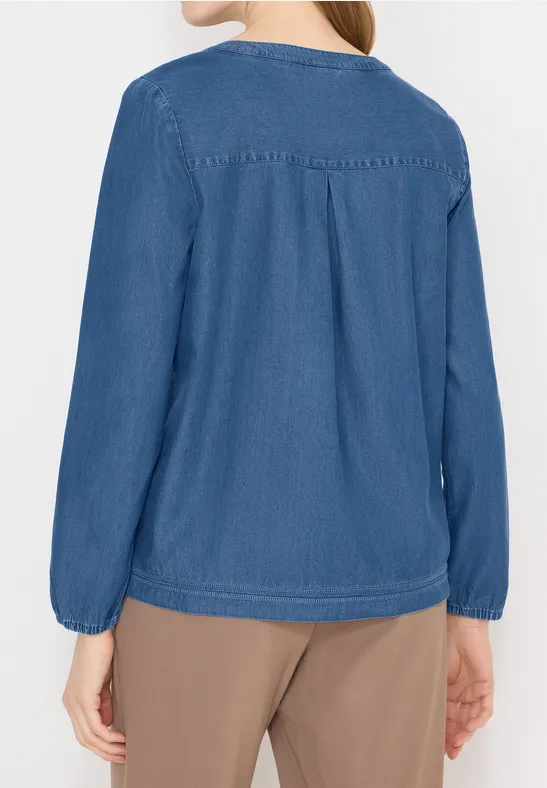 Rückansicht einer Person, die ein blaues Langarmshirt und beige Hosen trägt.