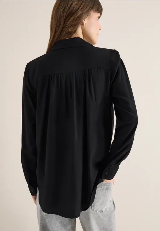 Frau von hinten in schwarzer Bluse und hellen Jeans.