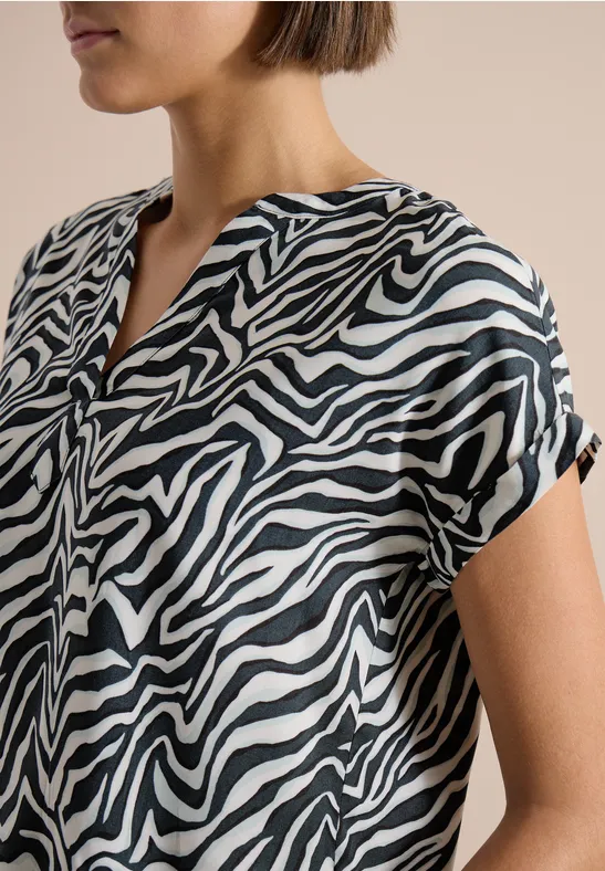 Damenbluse mit schwarz-weißen Zebramuster, kurzärmelig und locker geschnitten.