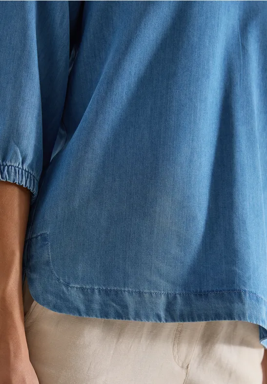 Haut ample en jean bleu à manches 3/4 élastiques porté avec pantalon beige.