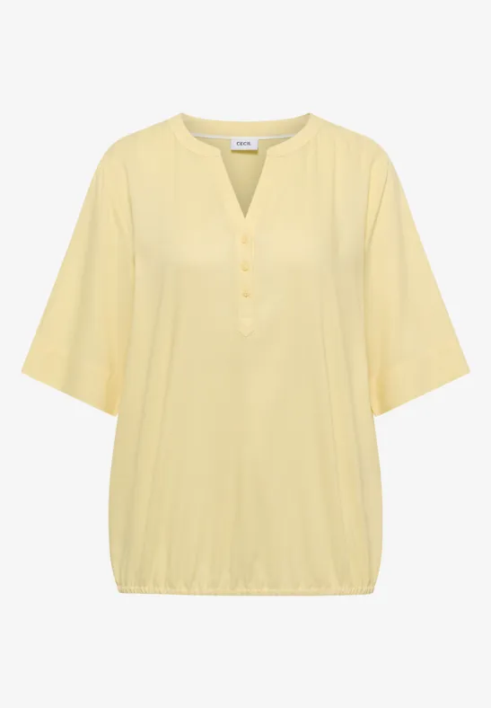 Haut féminin jaune clair à manches 3/4, encolure en V et patte de boutonnage.