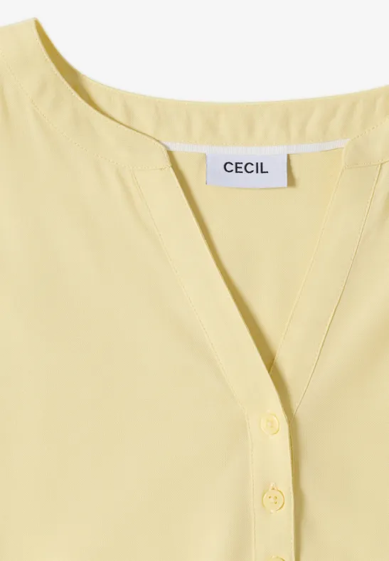 Blouse femme jaune pâle à encolure V et patte de boutonnage, étiquette 'CECIL' visible.