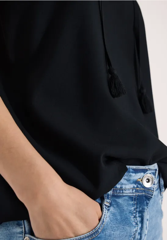 Personne en haut noir, main dans poche de jean bleu clair