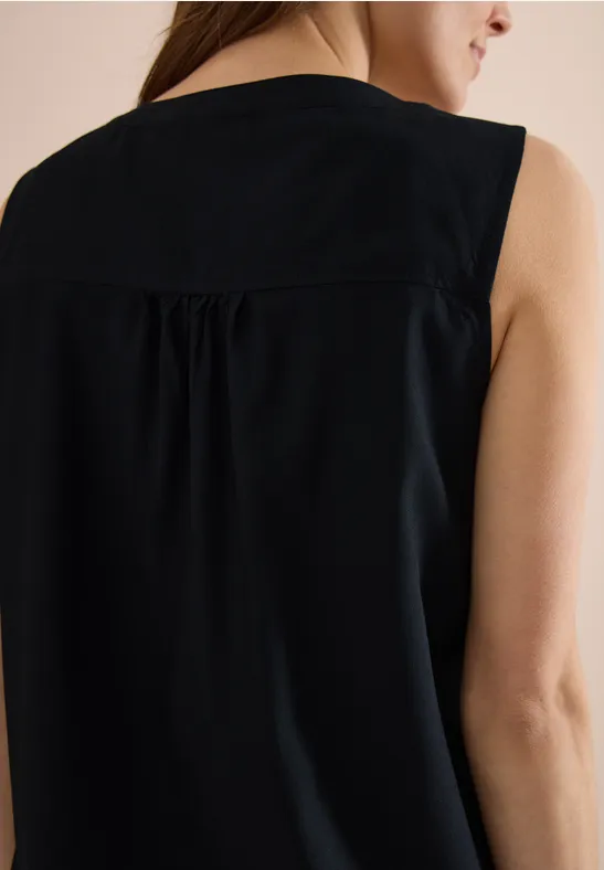 Vue arrière d'une femme portant un débardeur noir sans manches avec un pli discret dans le dos.